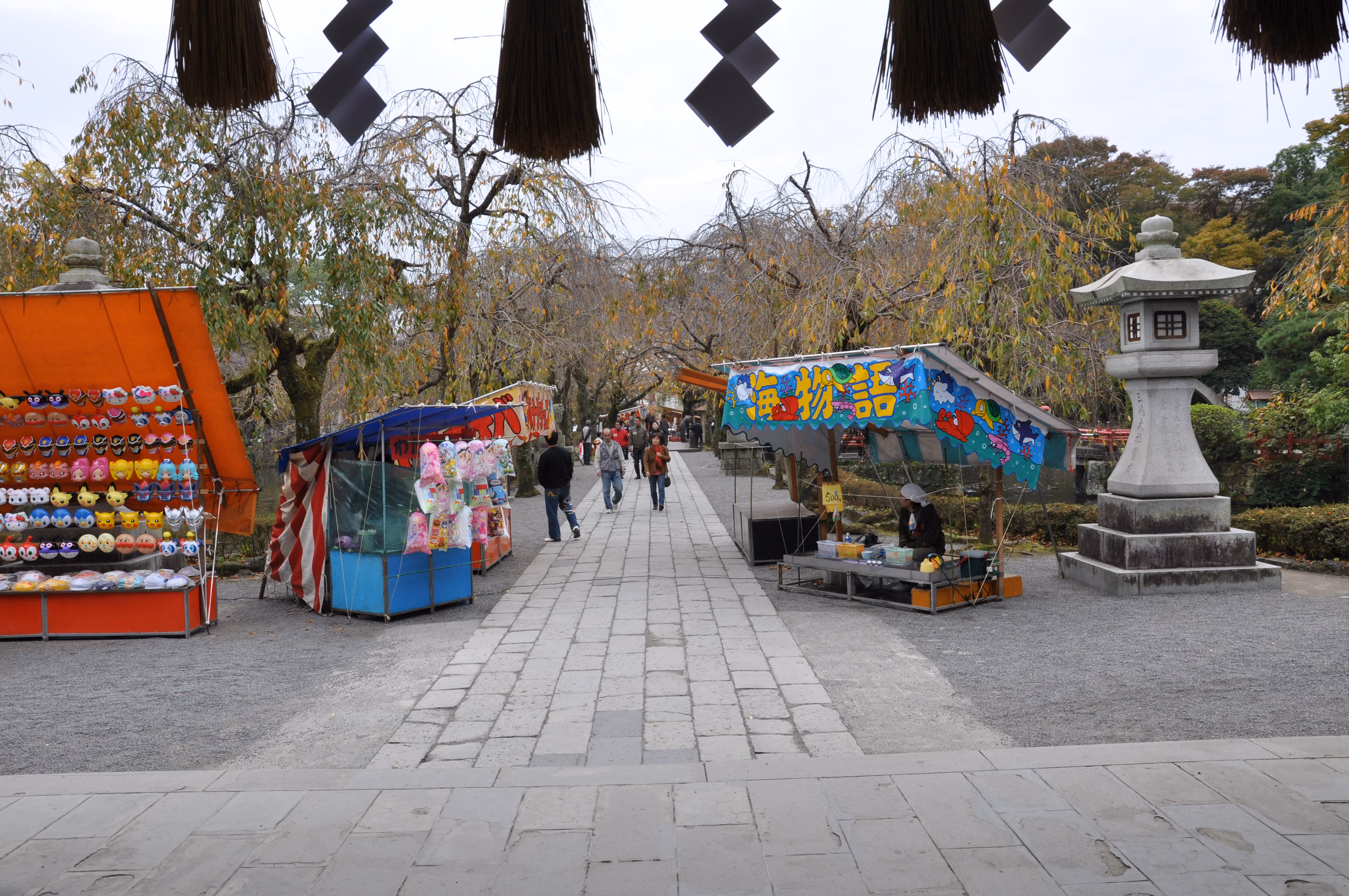 Approach path to Mishima Taisha lined with festival stalls under bare weeping cherry trees