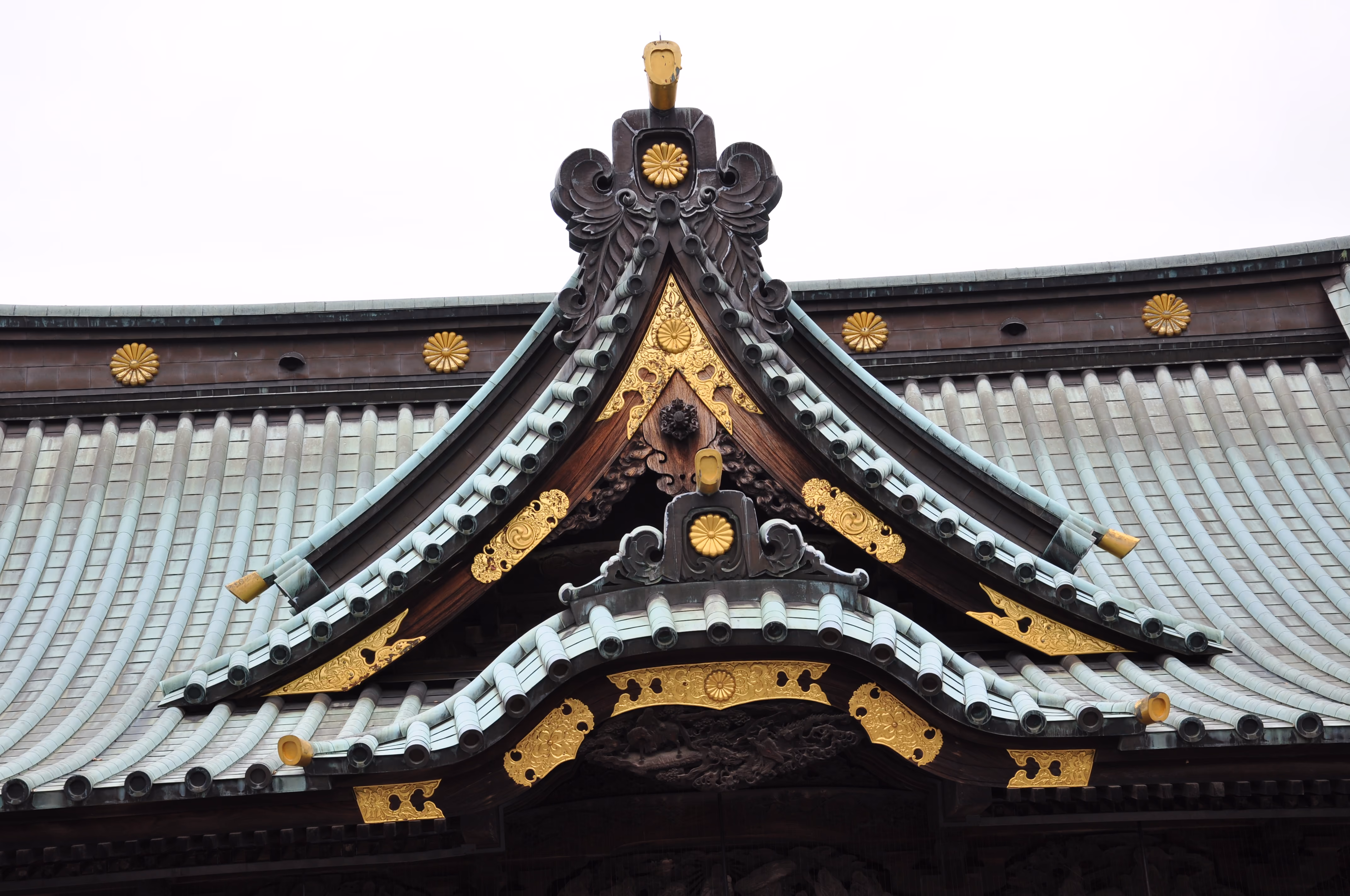 Close-up of gold chrysanthemum crests on a carved wooden gable ornament