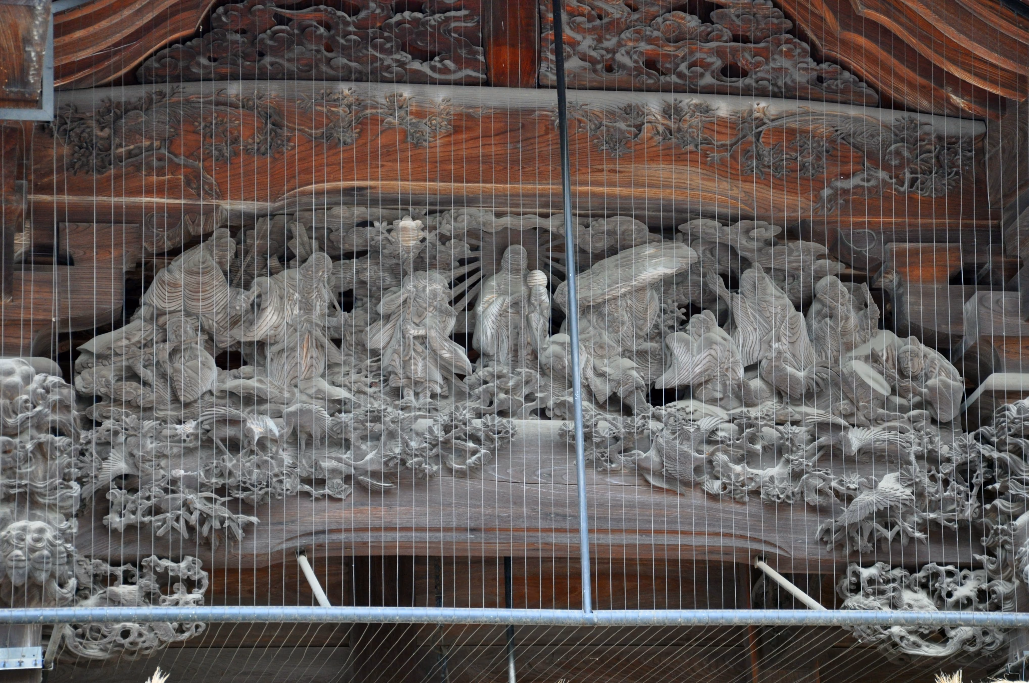 Wood relief carving of a large group of robed figures on Mishima Taisha's main hall