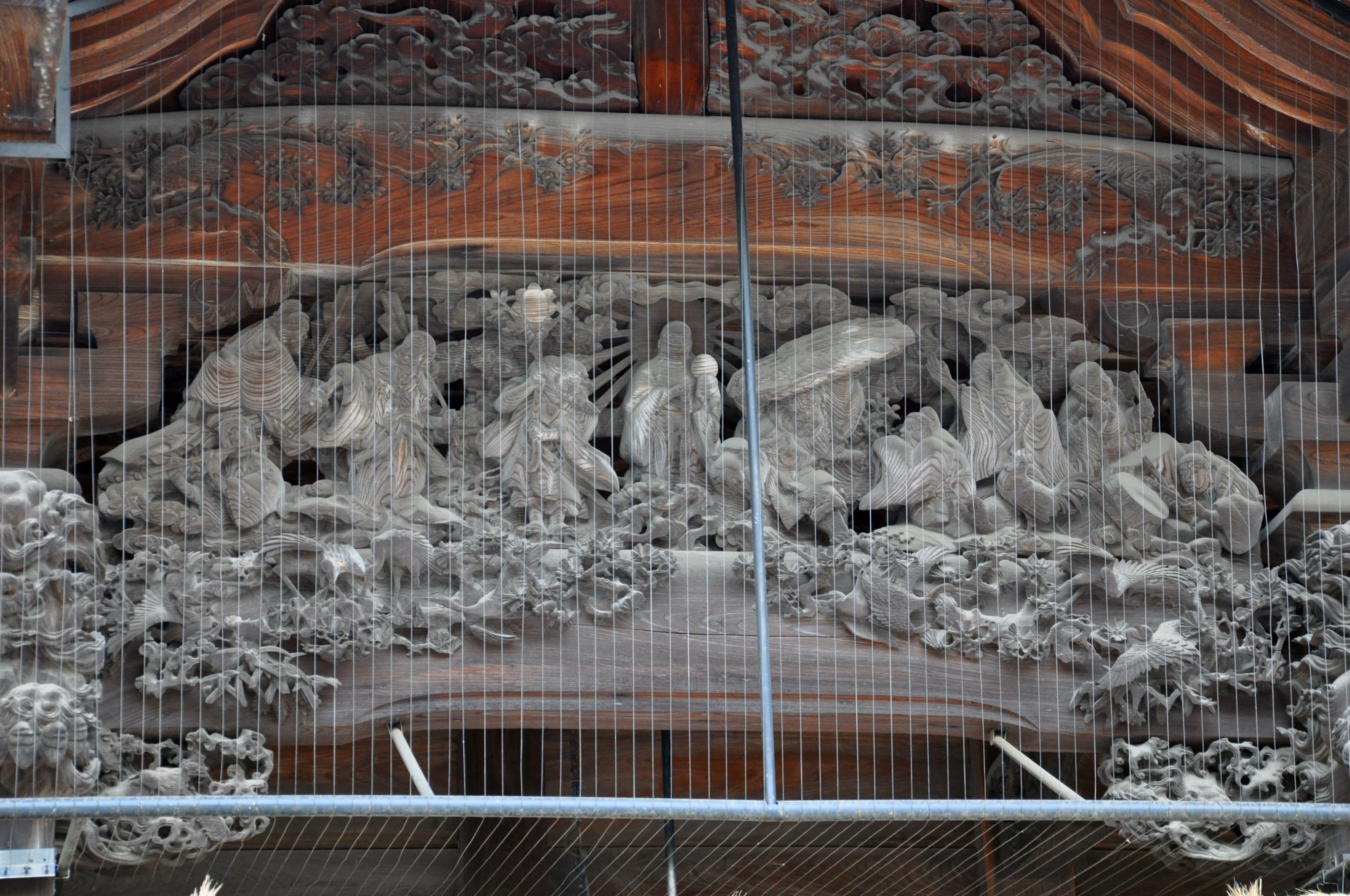 Wood relief carving of a large group of robed figures on Mishima Taisha's main hall