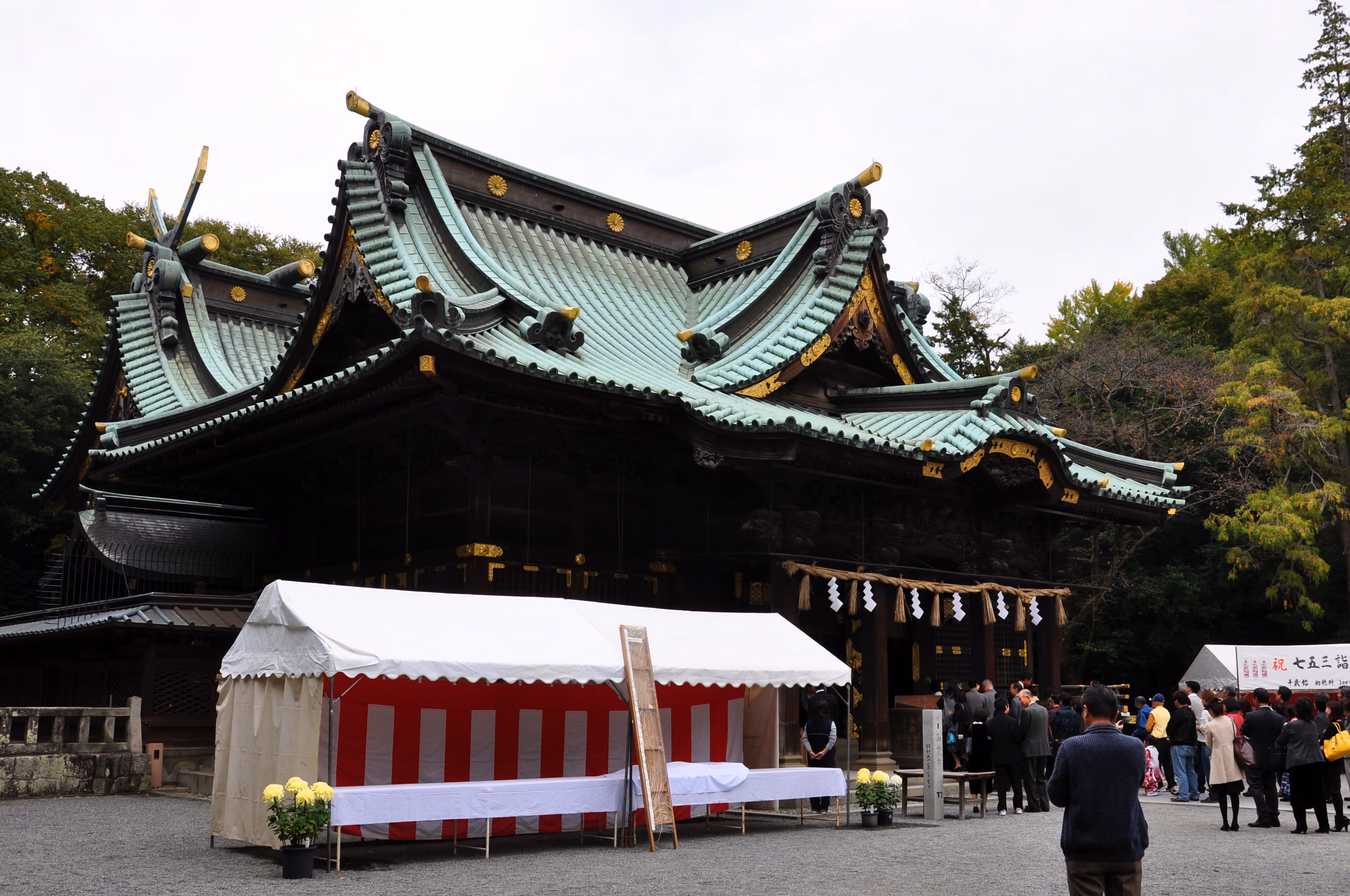 Visitors queuing under a white tent in front of Mishima Taisha's main hall