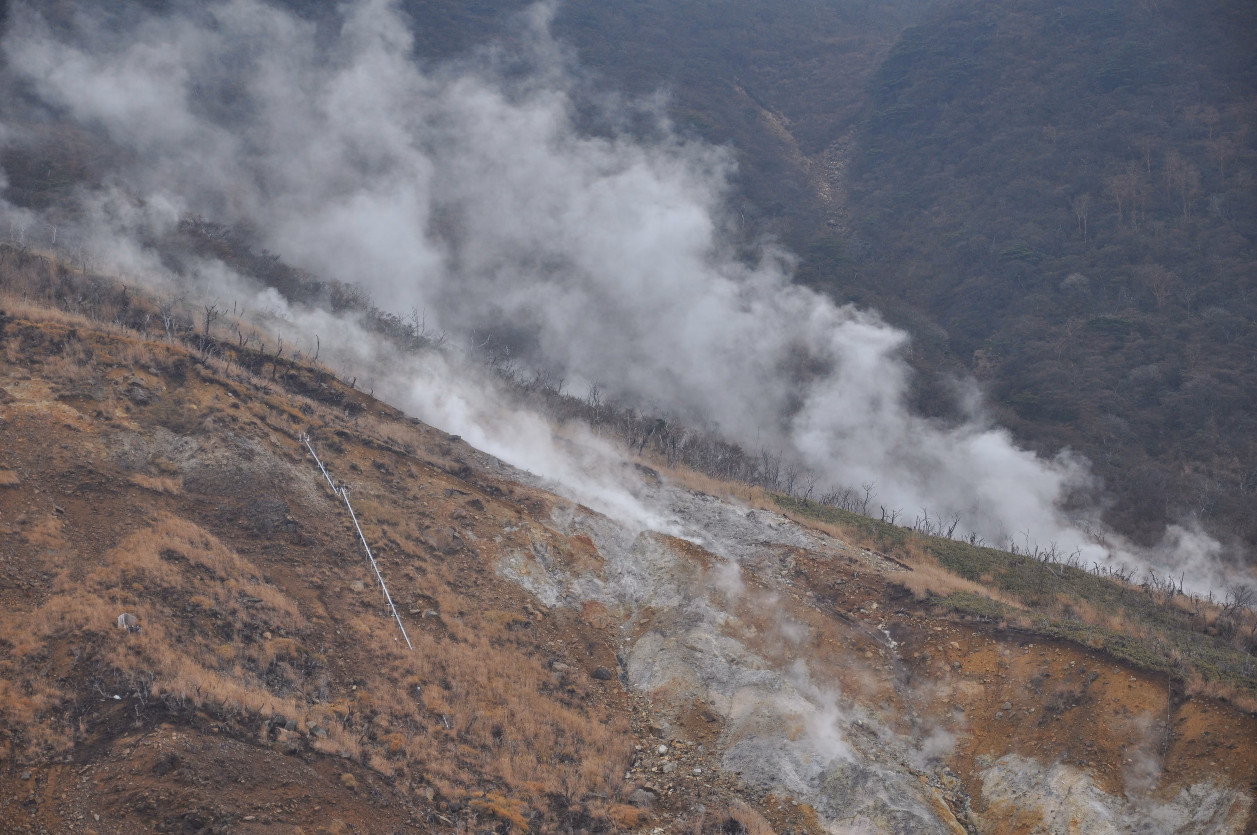 Steam pouring off a barren volcanic ridge at Owakudani, seen from a distance