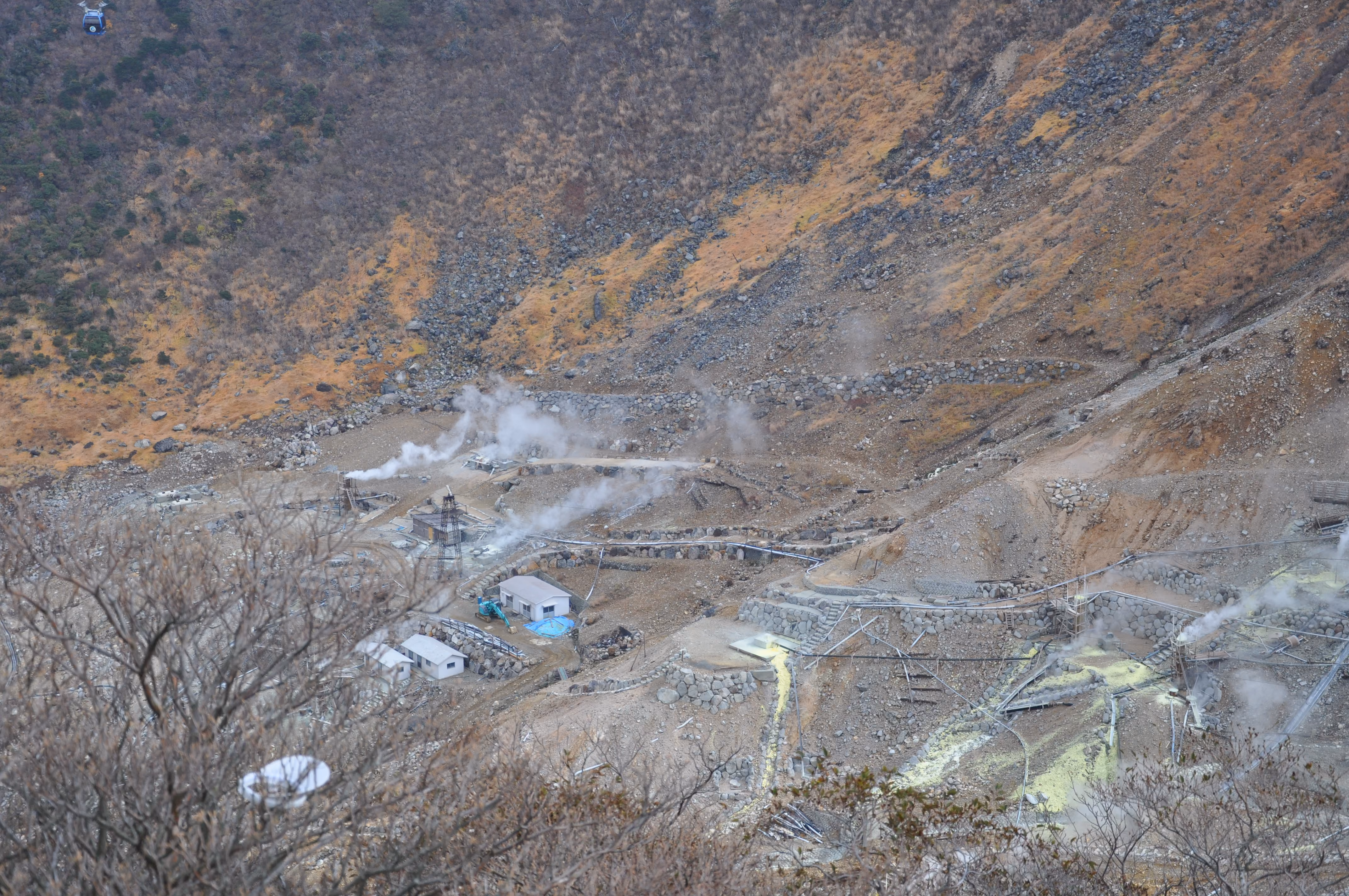 Aerial view of the sulfur works and steam vents on the valley floor at Owakudani, seen from a ropeway gondola