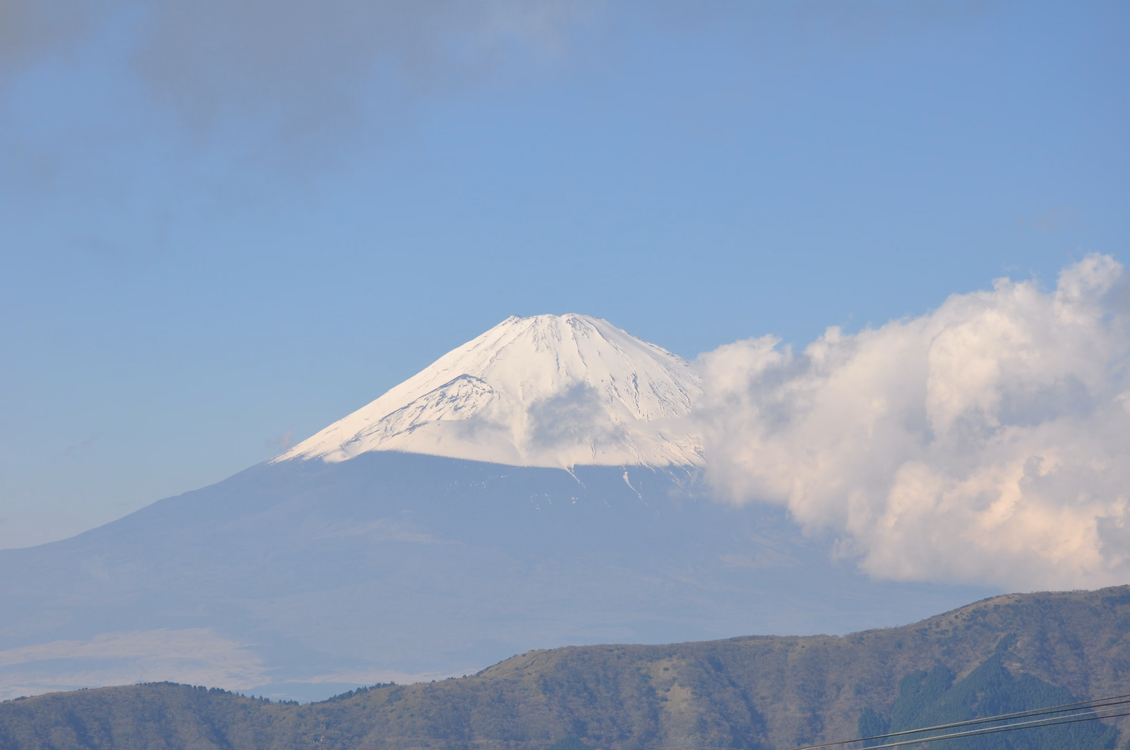 A clear, close view of Mount Fuji's snow-capped summit against a blue sky
