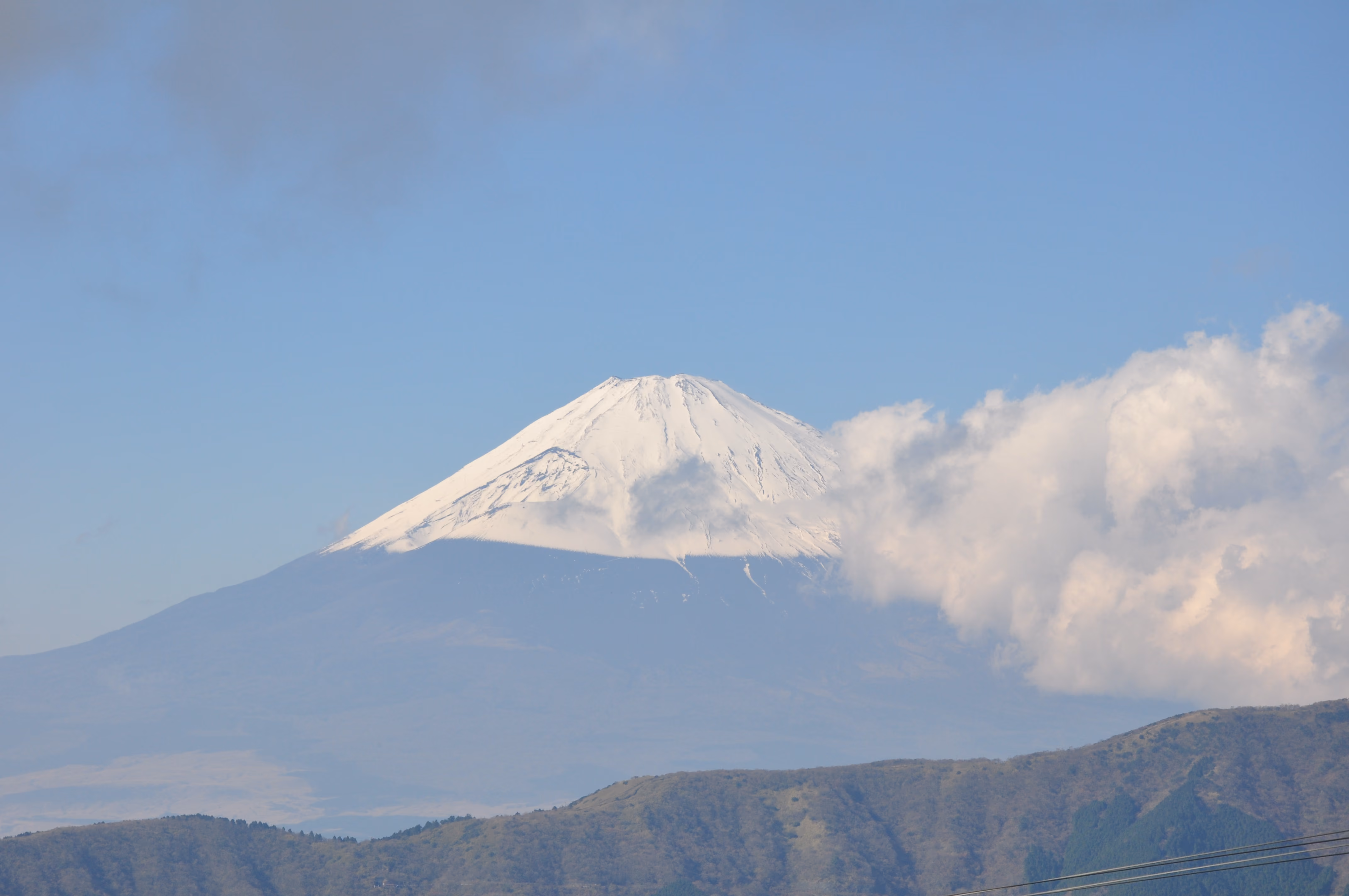 A clear, close view of Mount Fuji's snow-capped summit against a blue sky