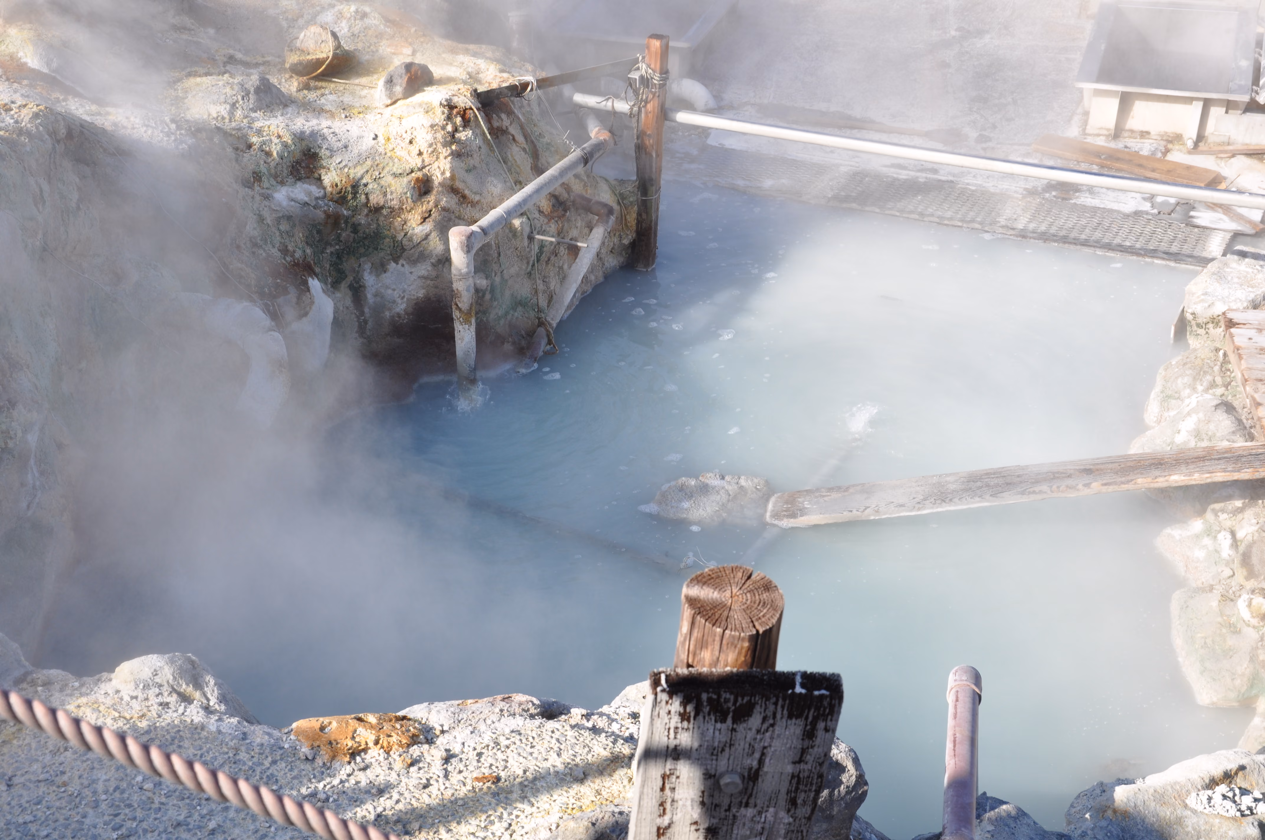 Close view of a milky blue-white hot spring pool at Owakudani, steam rising off the surface