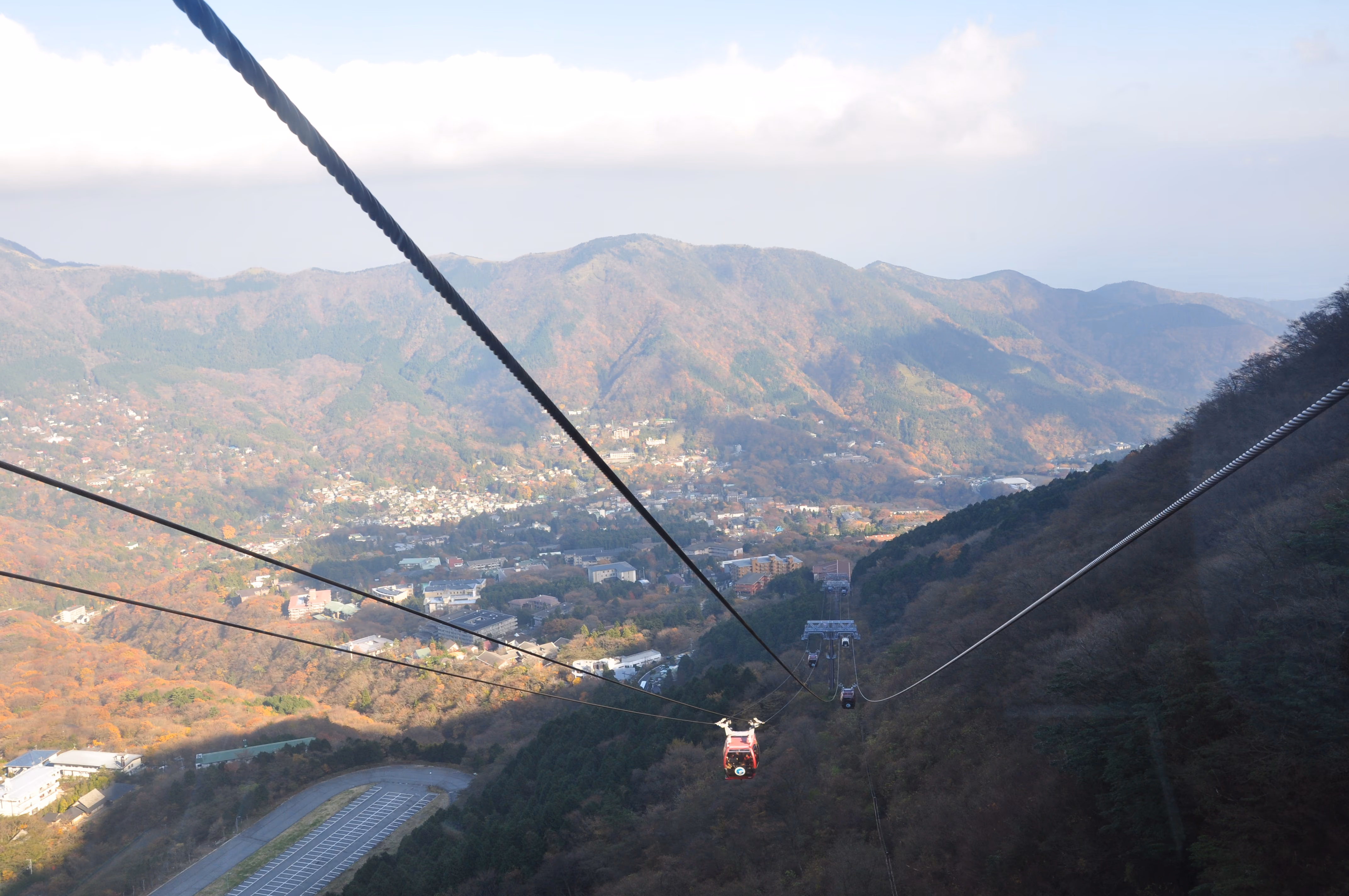 A Hakone Ropeway gondola descending over the town of Gora, surrounded by autumn foliage