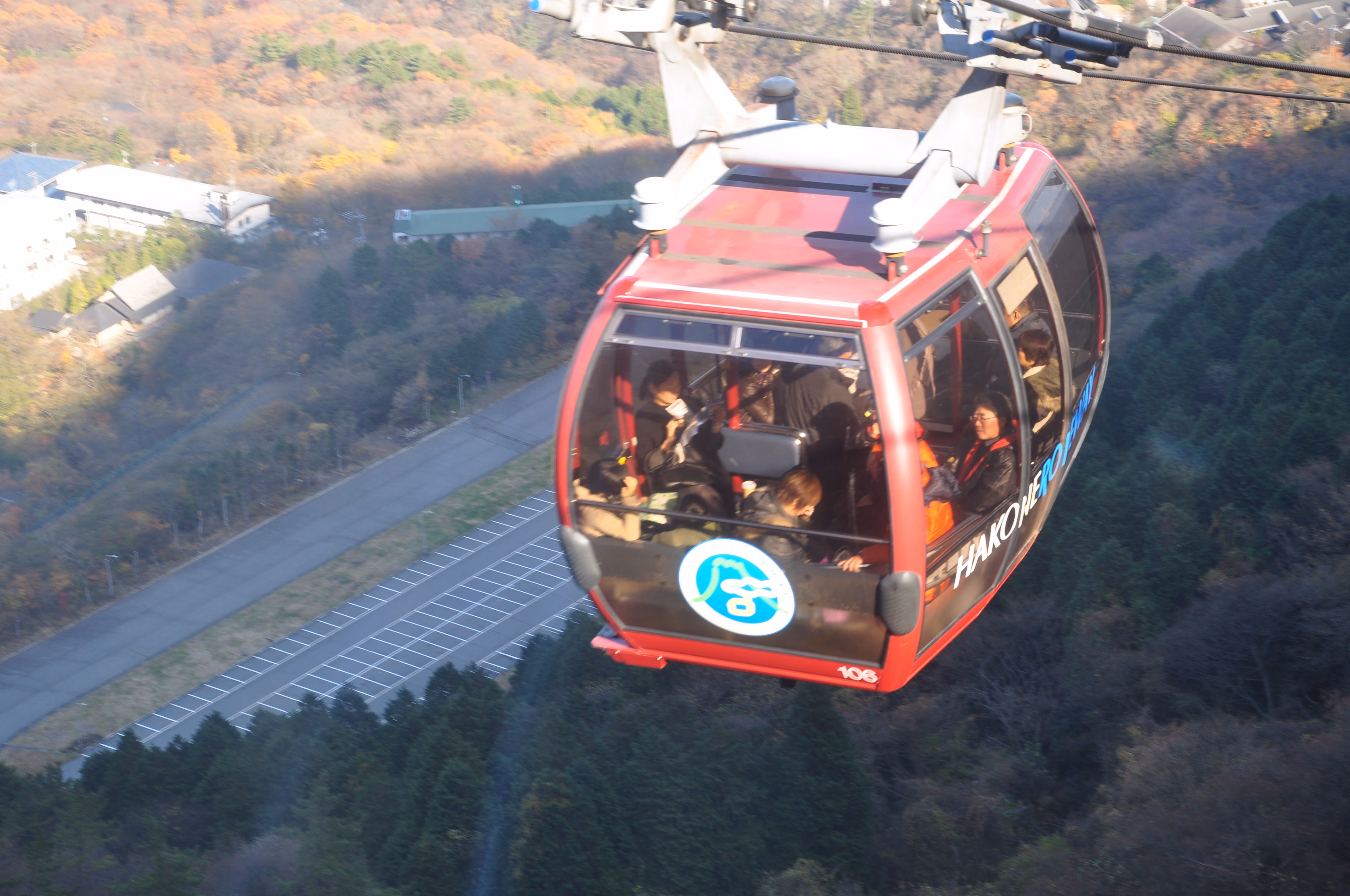 Interior of a crowded Hakone Ropeway gondola cabin descending over a forested hillside