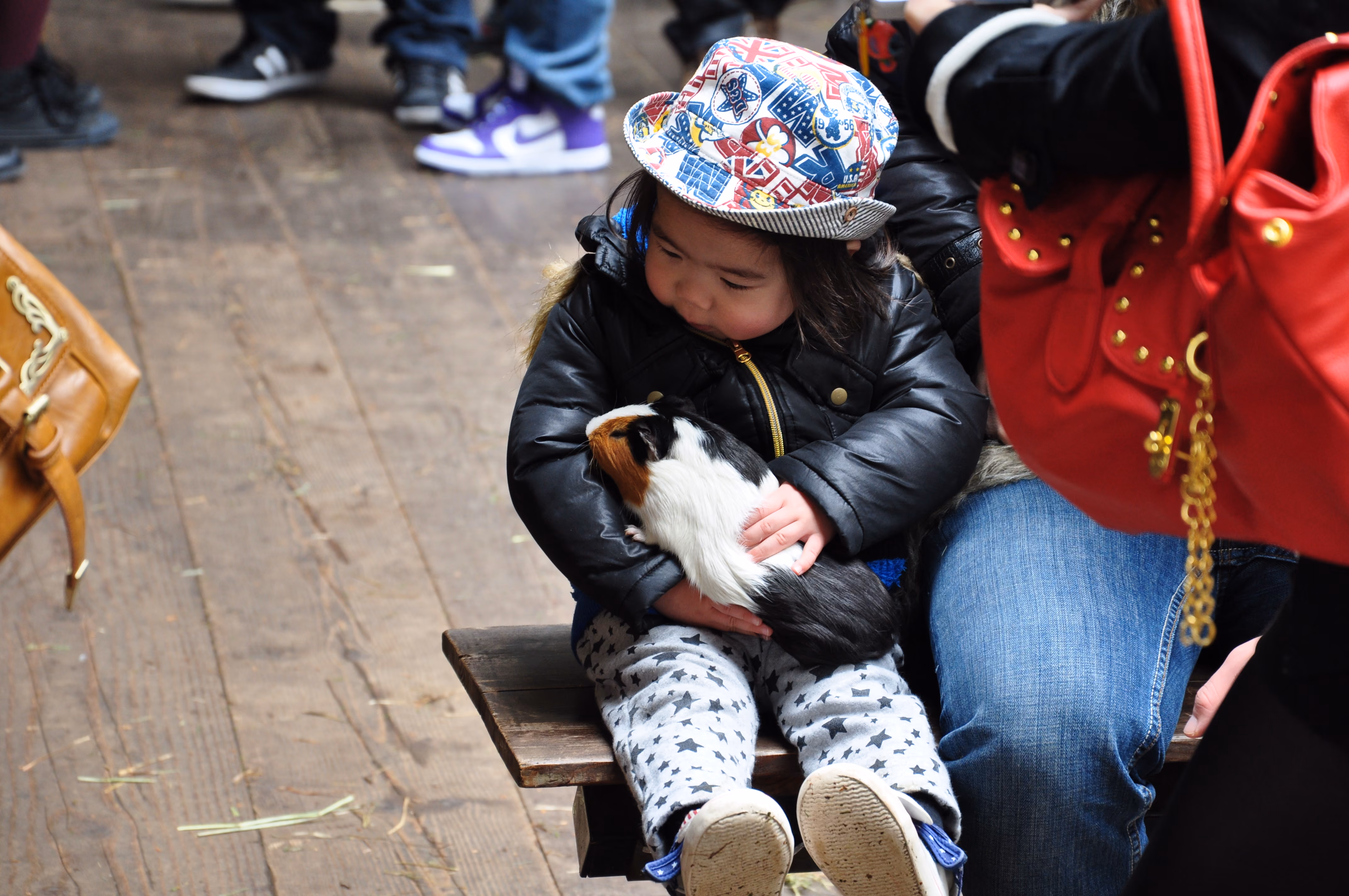 A young child in a bucket hat holding a guinea pig