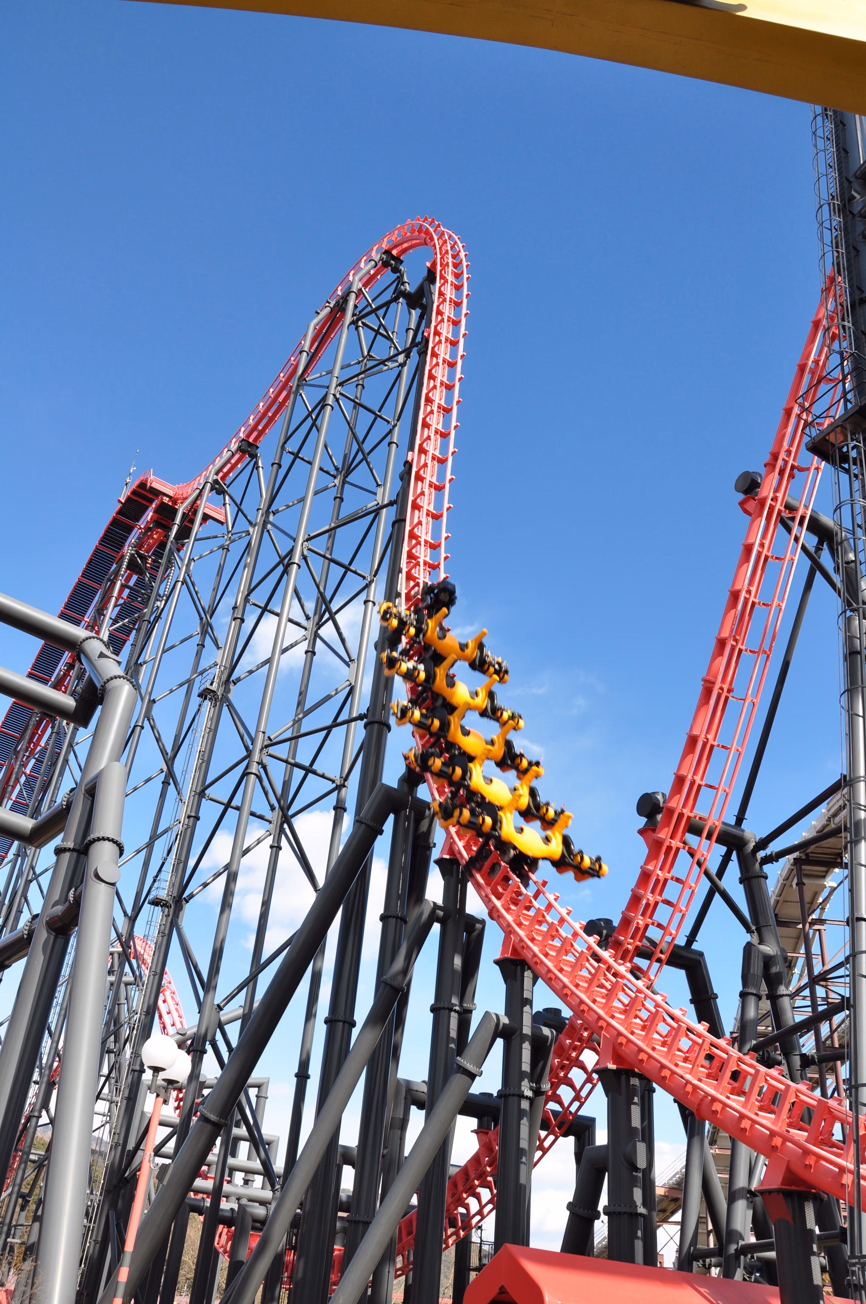 Eejanaika roller coaster with rotating yellow seats cresting a red steel track