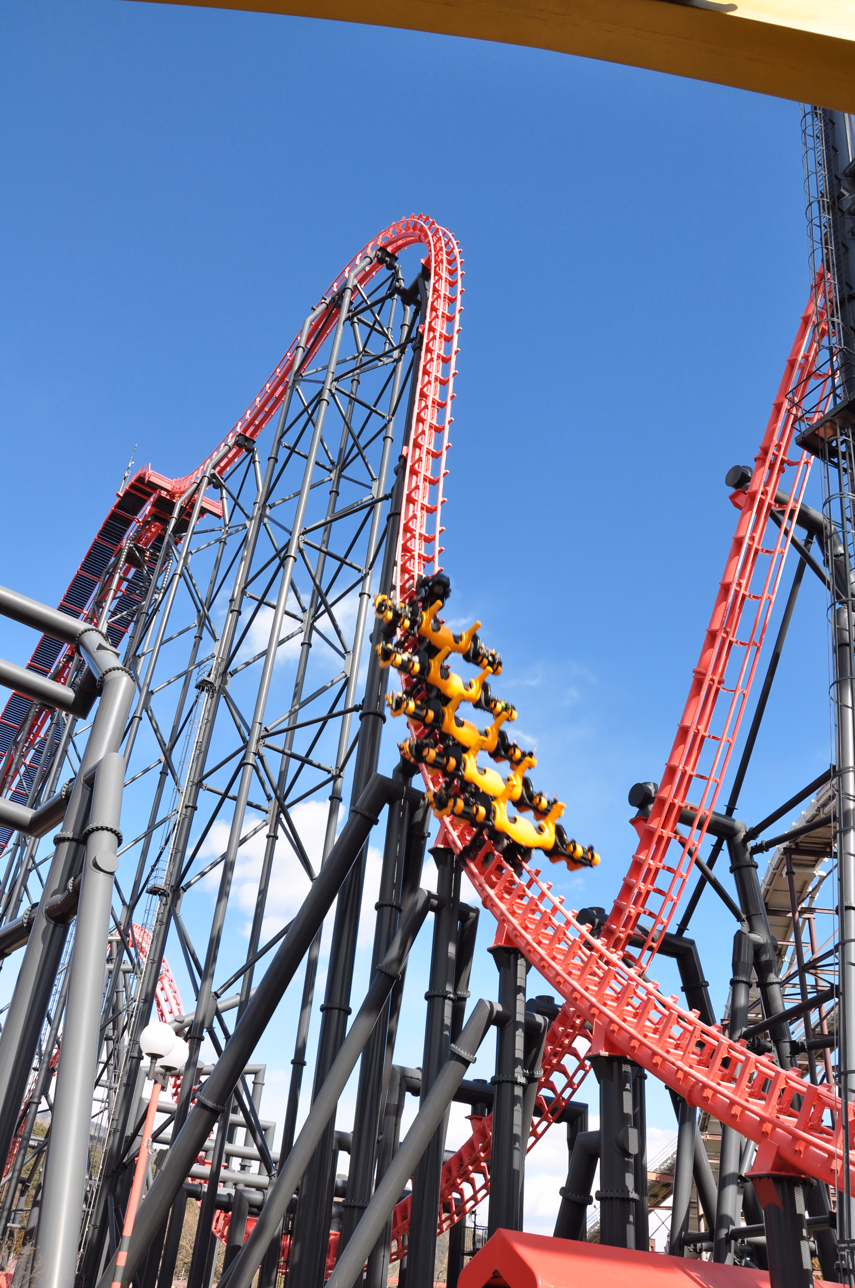 Eejanaika roller coaster with rotating yellow seats cresting a red steel track