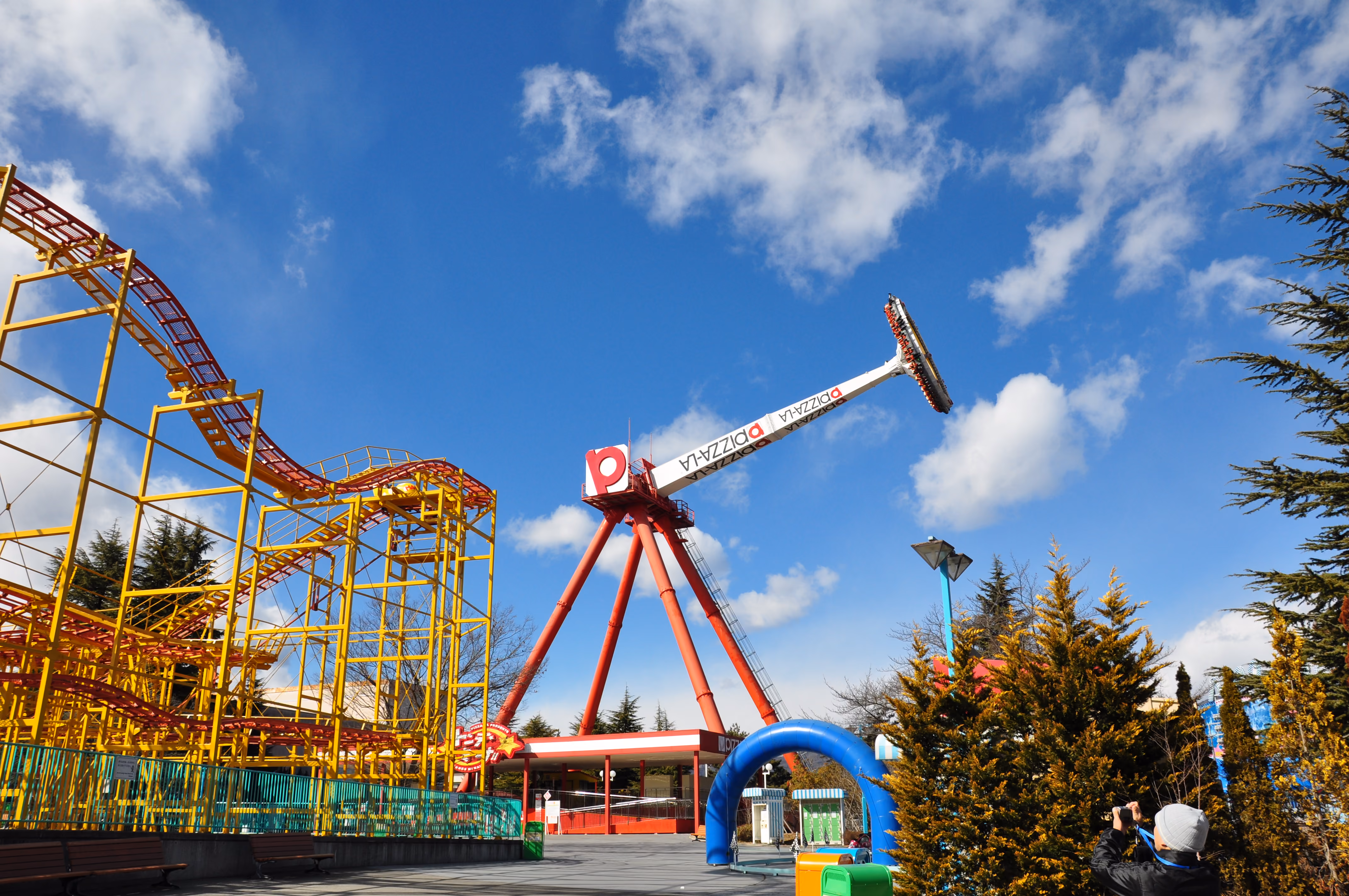 A pendulum amusement ride swinging riders upside down against a blue sky