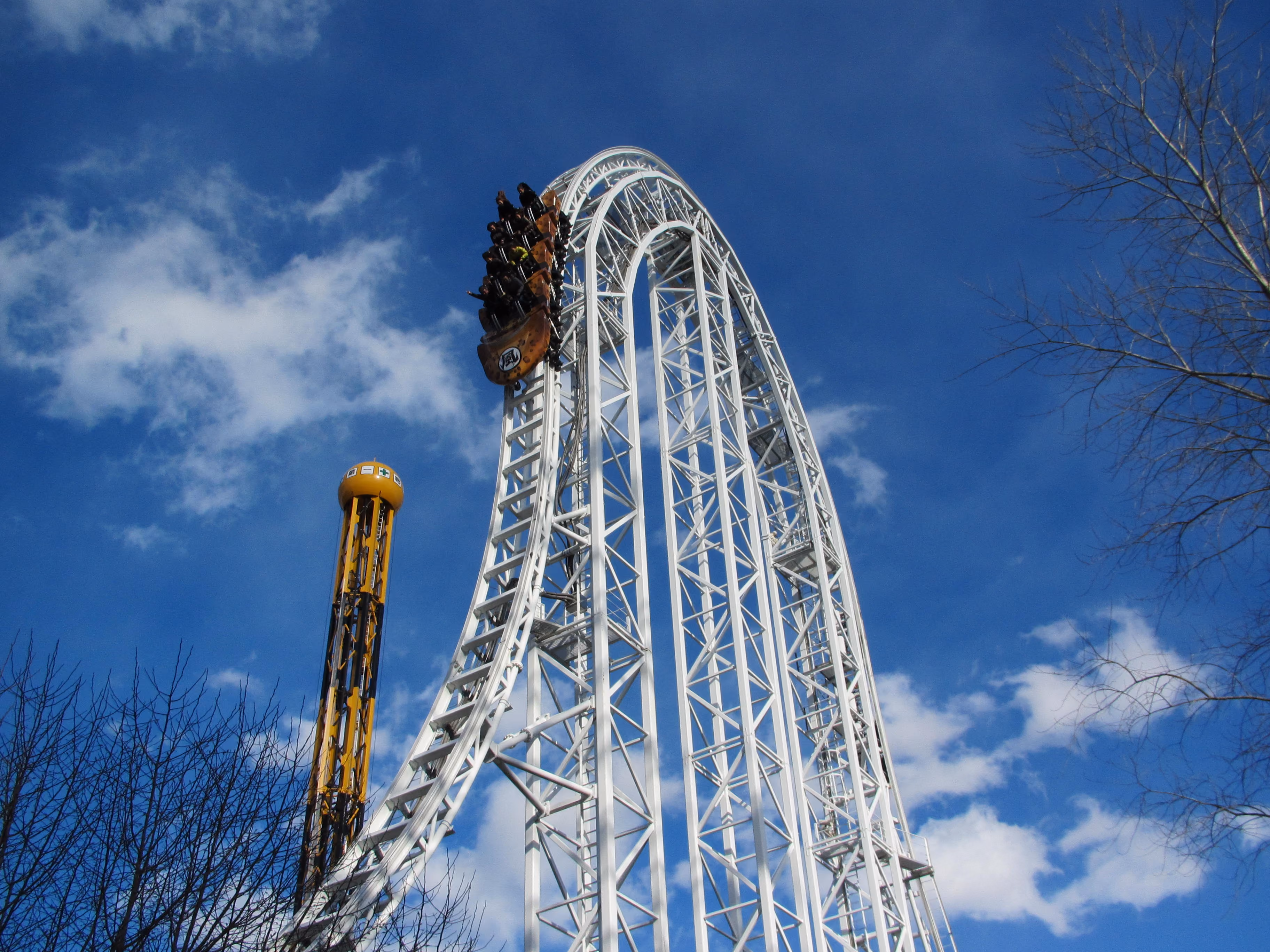 Fujiyama roller coaster's arched track and Dodonpa's yellow launch tower against a blue sky
